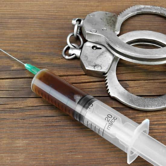 Hypodermic needle laying next to handcuffs