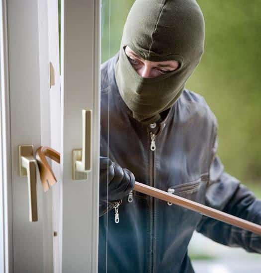 Masked man breaking into a home with a crowbar