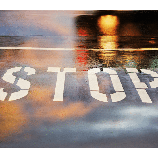 a wet road with "Stop" painted on the asphalt